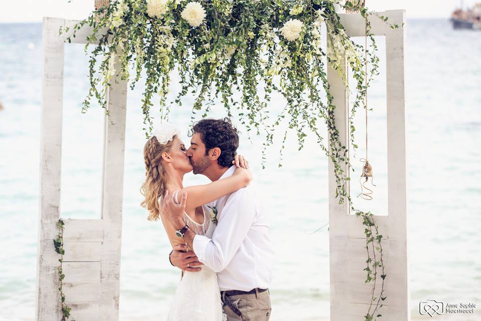 Young newlywed couple kissing under a flower arrangement